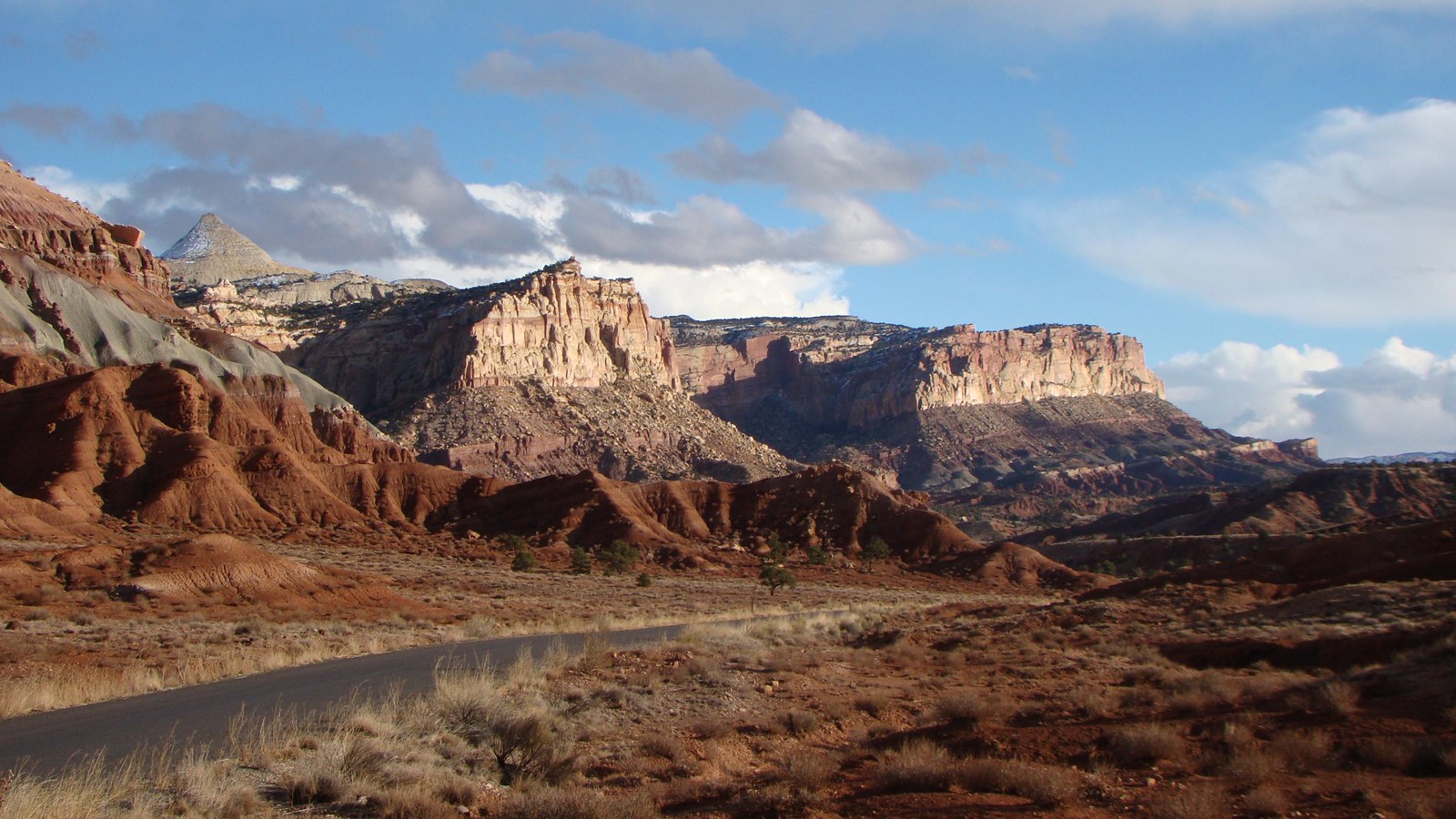 a road parallels sandstone cliffs