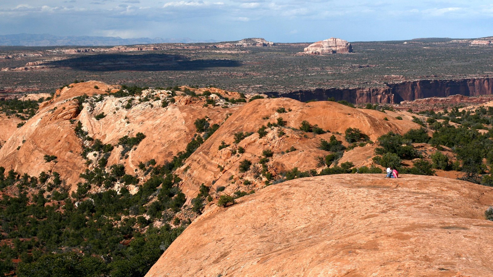 Two hikers atop sloping sandstone features