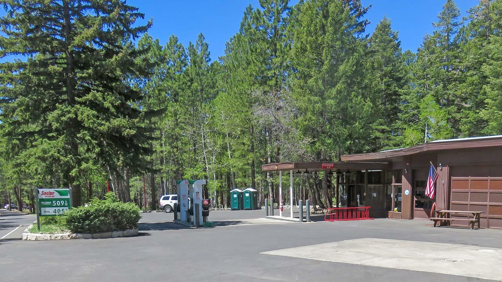 a rustic brown building with garage doors and two gas pumps out front.