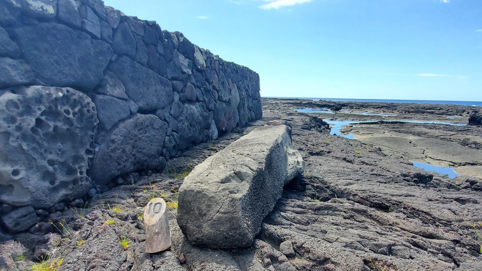 A long rectangular boulder sits next to a heiau platform