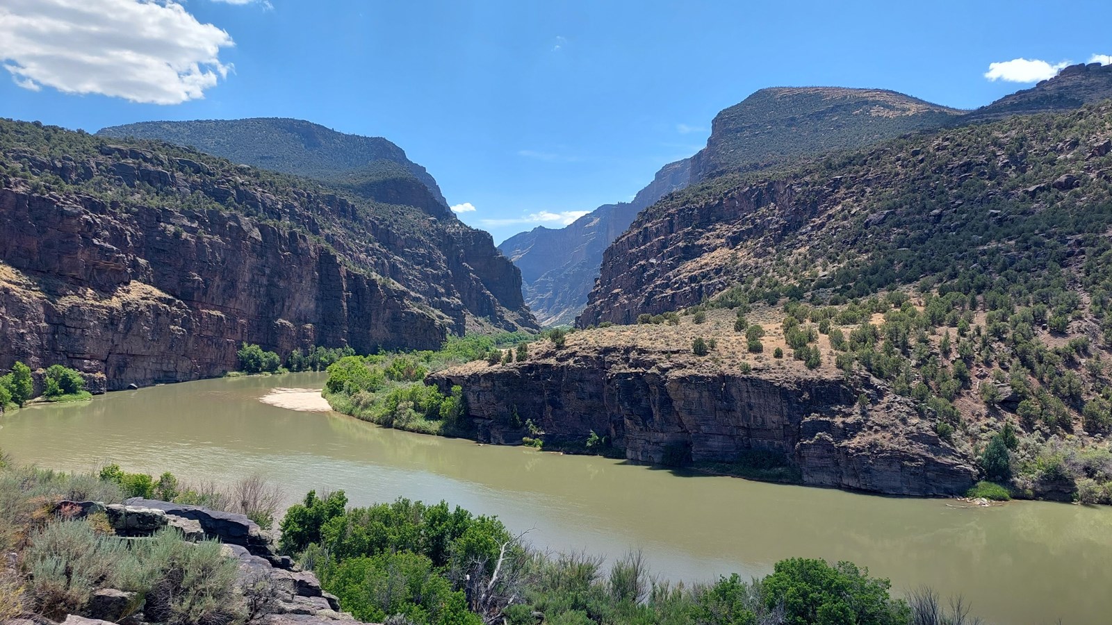 A steep, rugged river canyon, surrounded by desert shrublands.