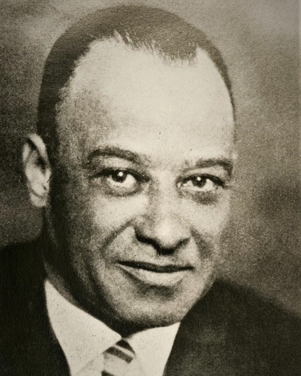 An African American man in dark jacket and tie.