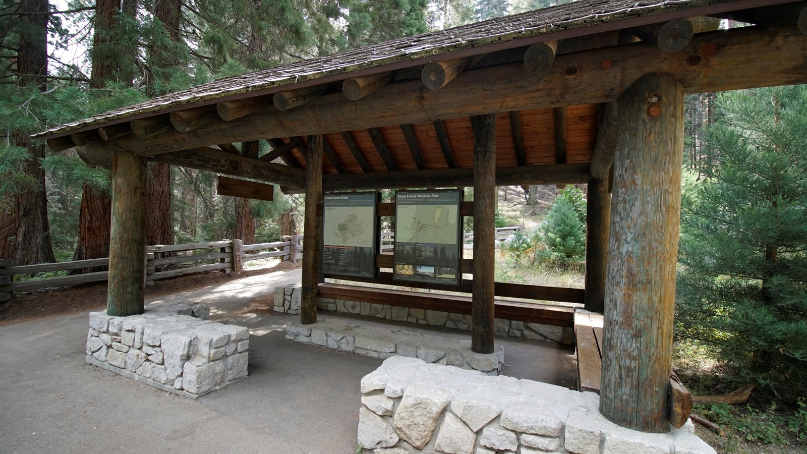 A brown roof stands over a wooden panel. On the panel is information about trails