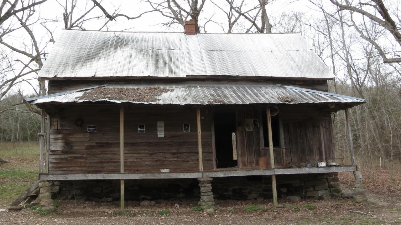 A wooden cabin with a sheet metal roof on a cloudy day. 