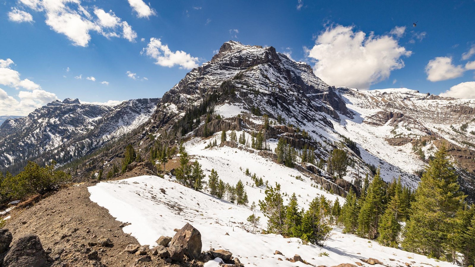 A rocky, snow-covered mountain peak as viewed from a mountain pass.