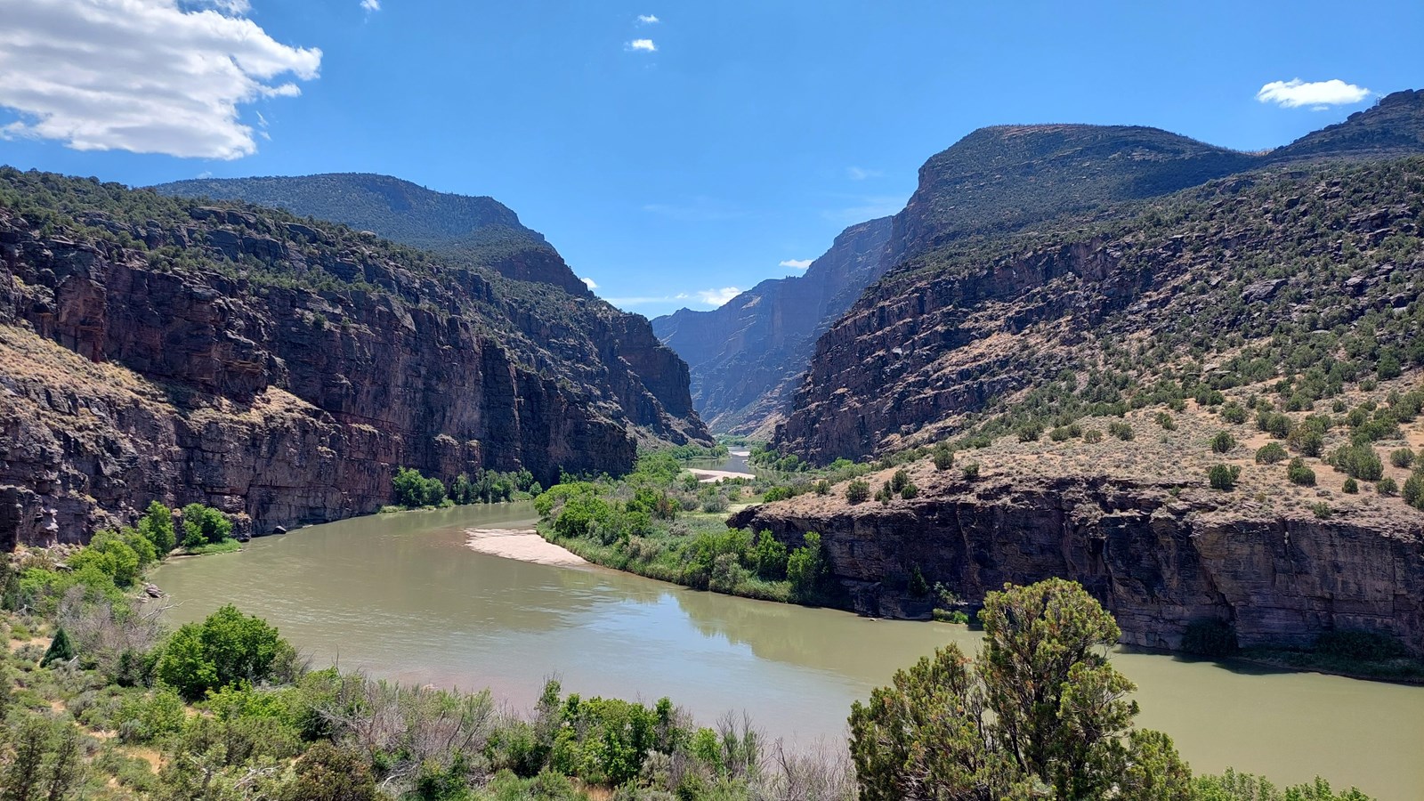 A steep, rugged canyon with a flowing river, surrounded by desert shrubland scenery.