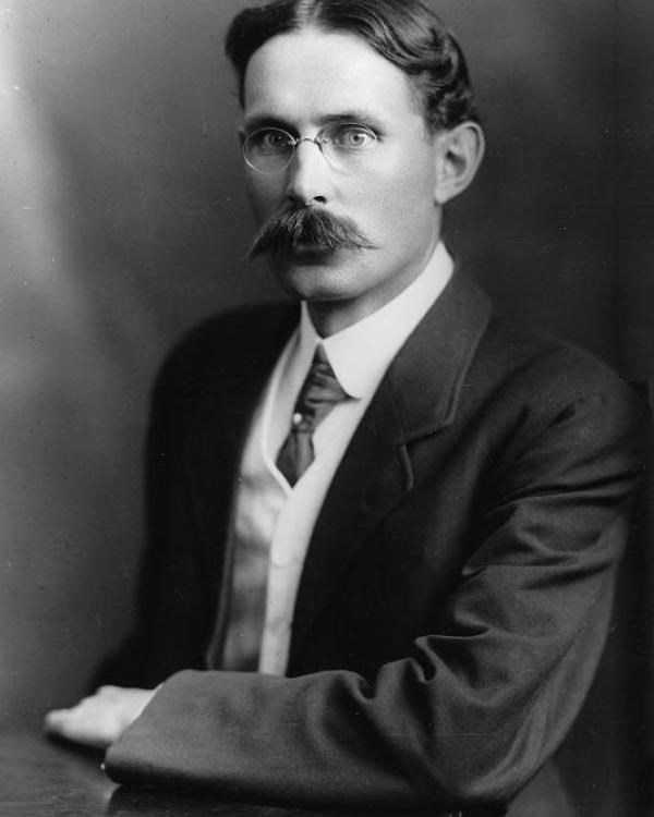 Man in suit and glasses poses for a picture