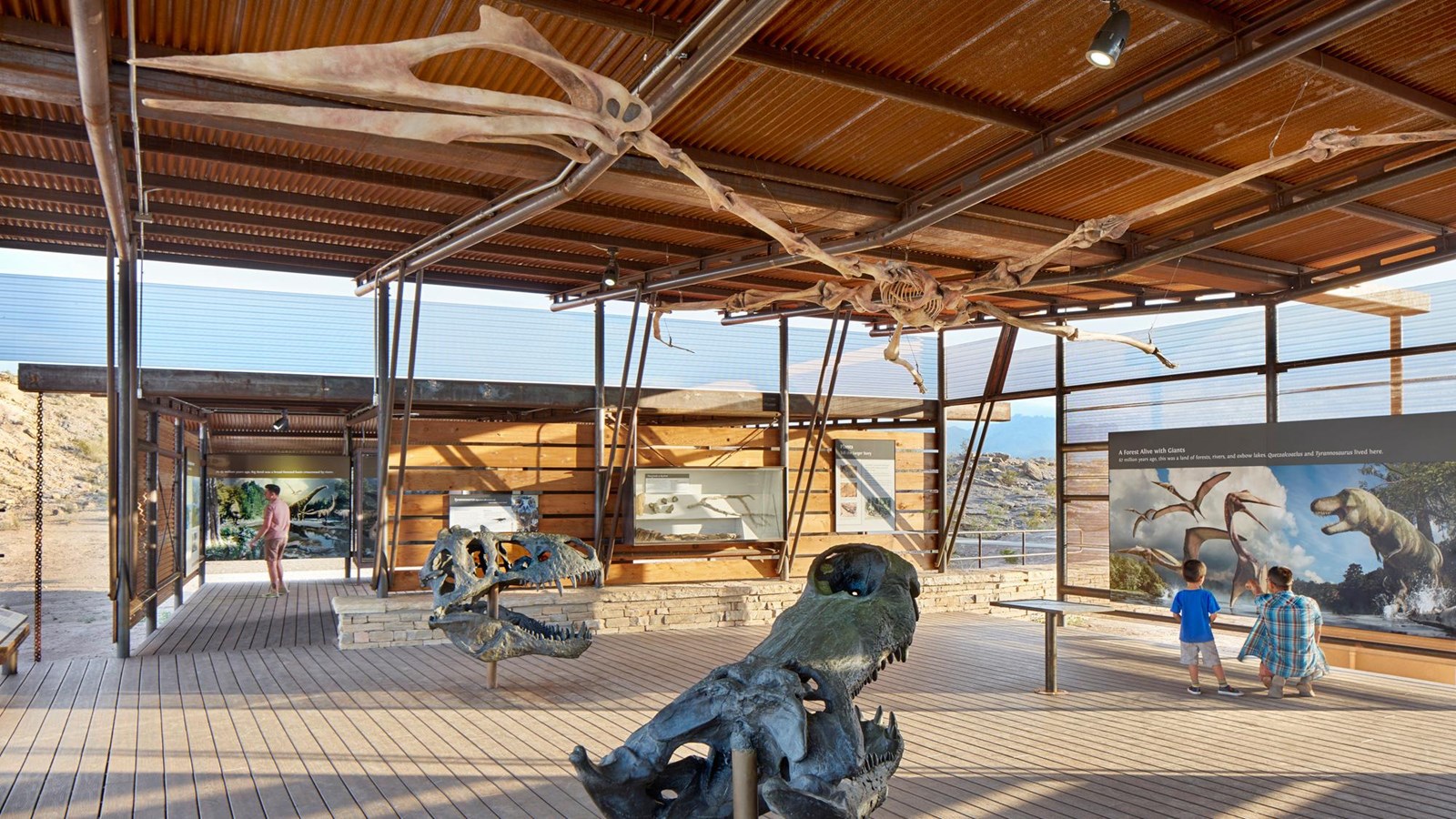 A large room contains casts of dinosaur fossils and exhibits discussing geology and paleontology. 