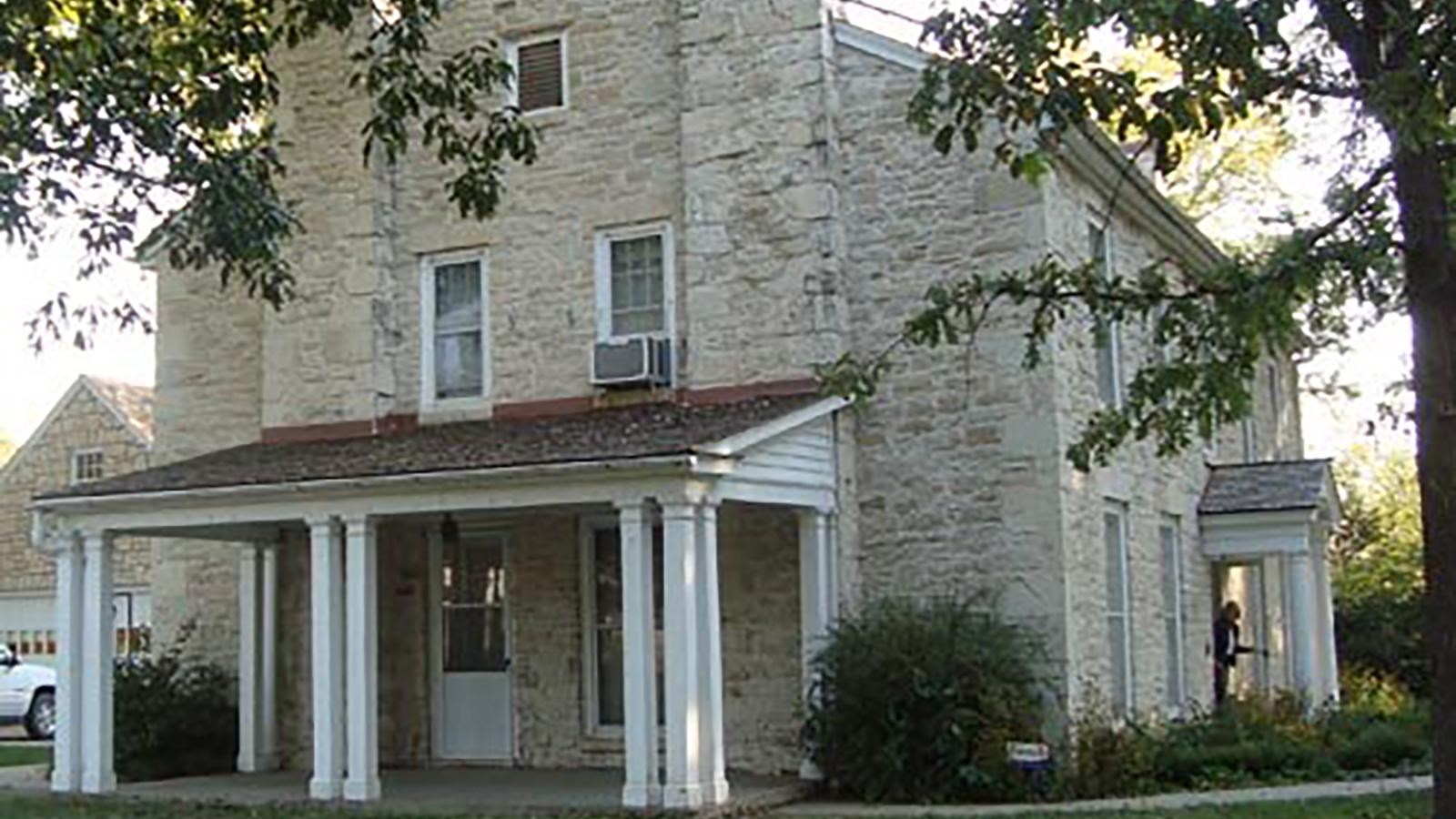 Large, white stone historic house with a covered porch.