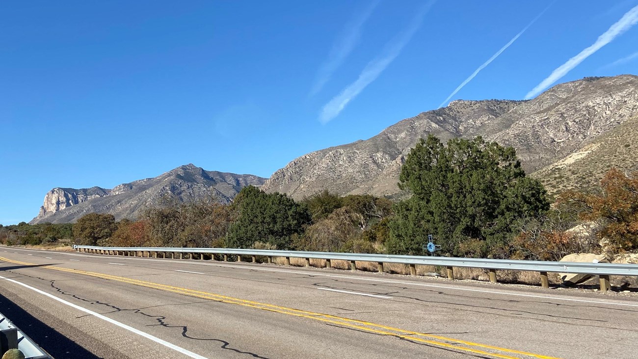 Desert mountians rise past a paved highway. 