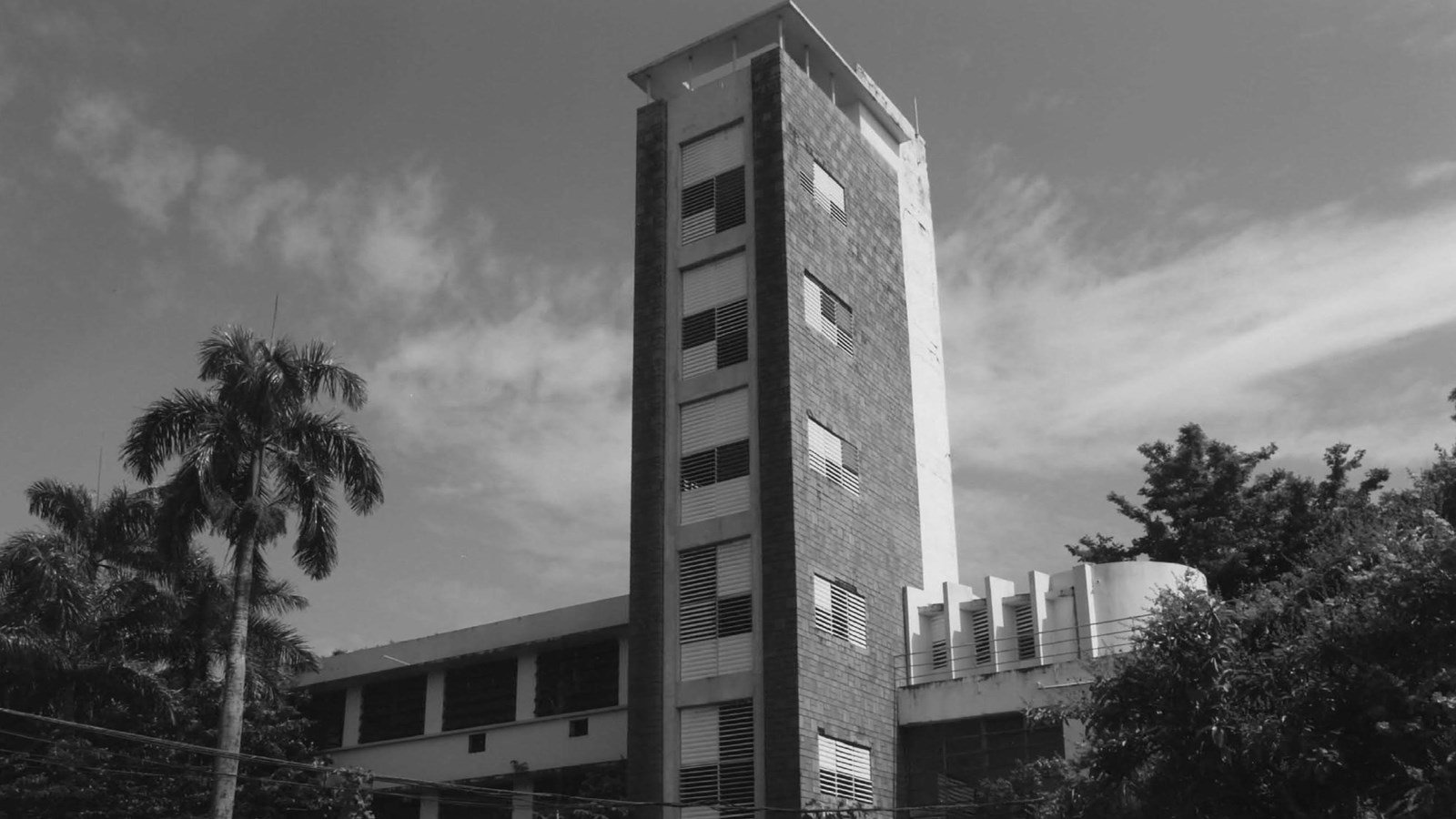 Two-story factory with a six-story tower, with sign that says 