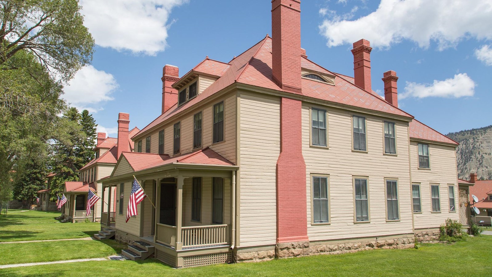 A historic building with pale yellow siding and a roof with red shingles.