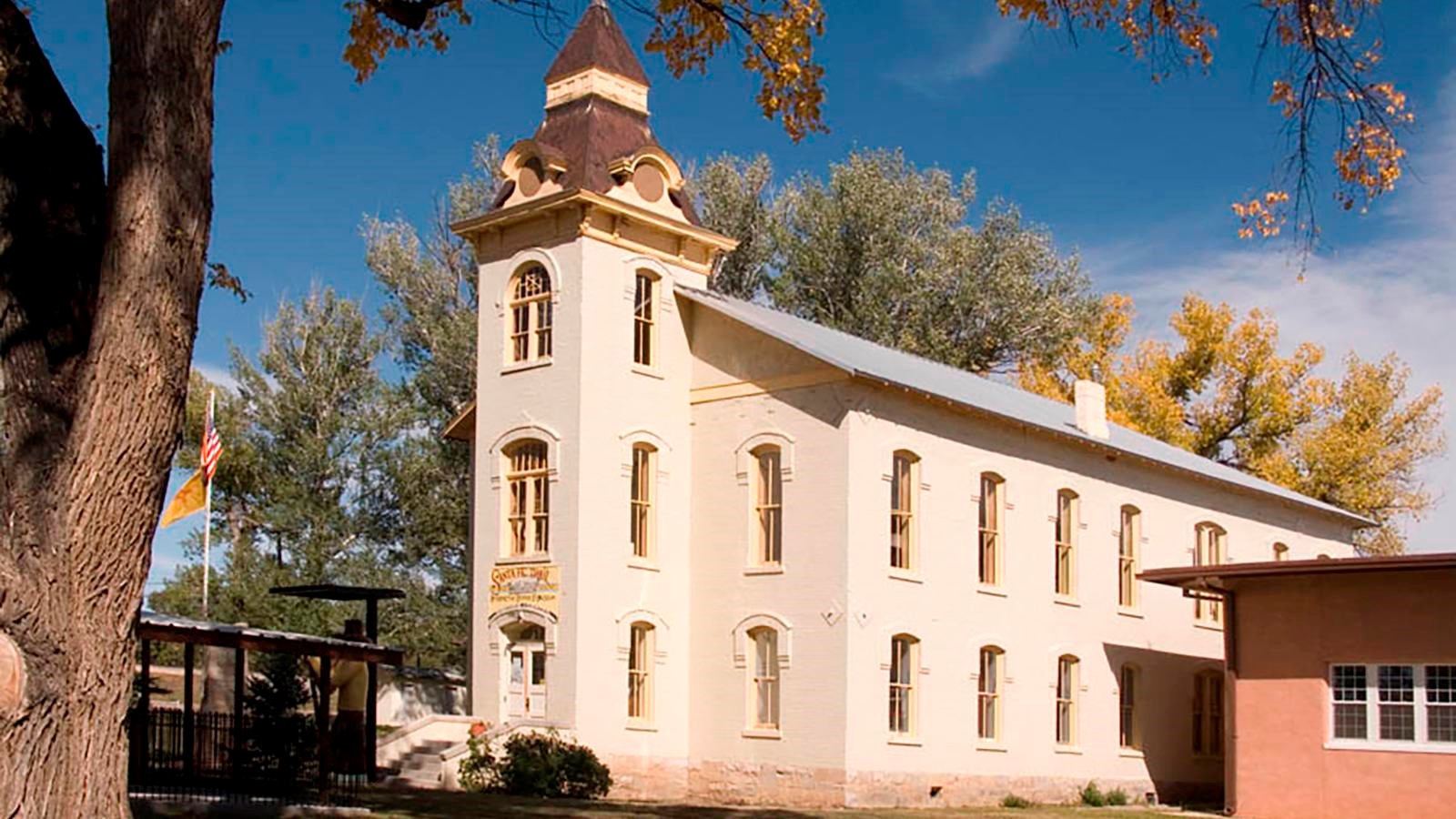 A historic stone courthouse building under large towering trees.