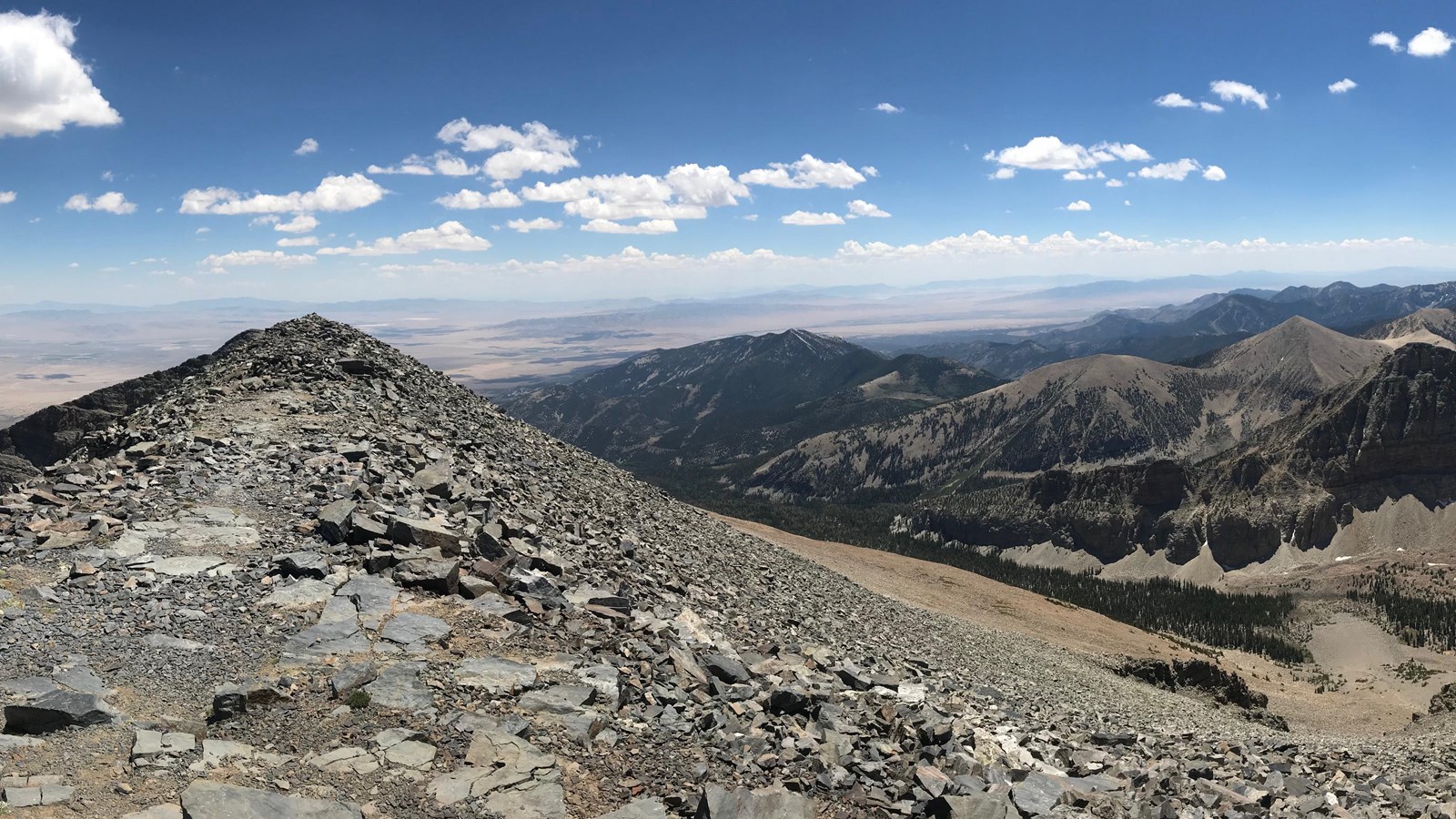 View from wheeler peak with blue skies and rocky mountain peaks.