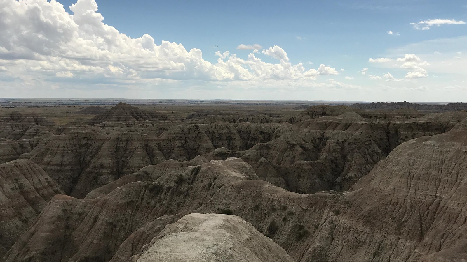 Rolling, expansive badlands buttes stretch out under blue sky.