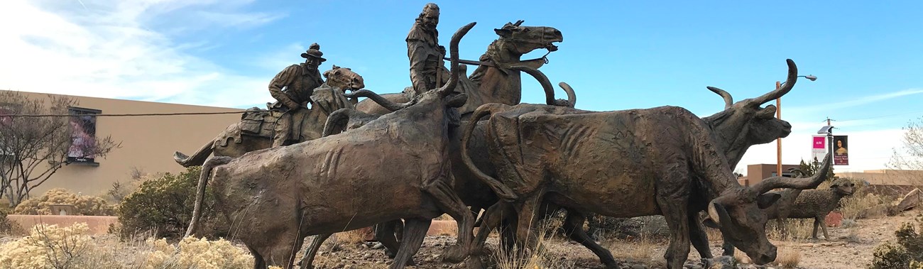 A bronze statue of oxen and traders set in the desert.