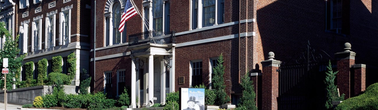 Photograph of outside of Woodrow Wilson House with street in foreground. 