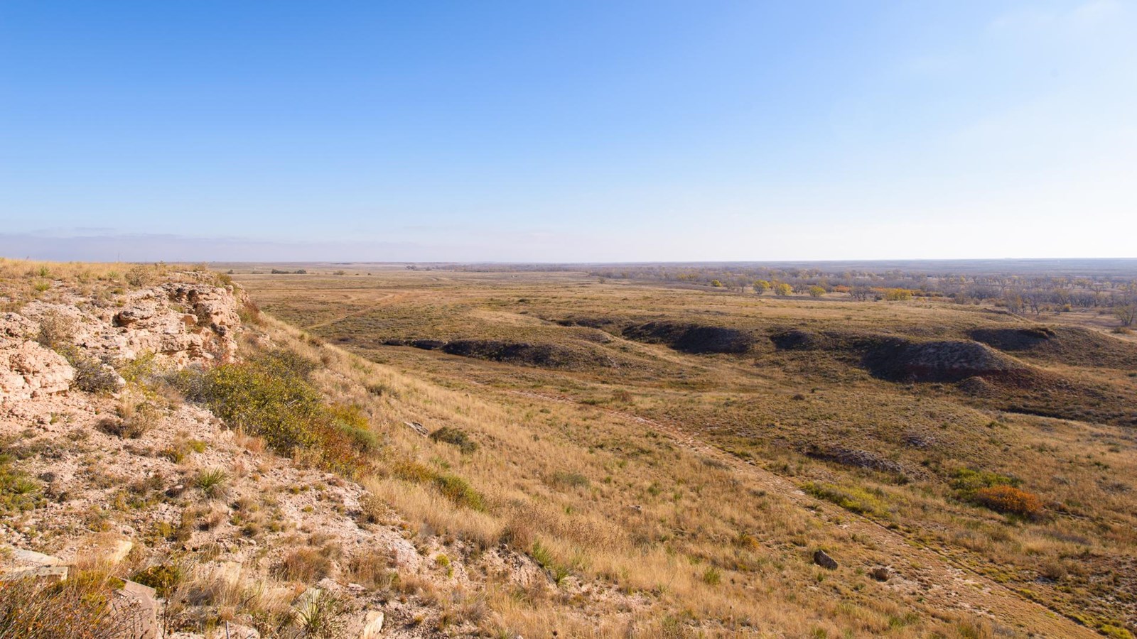 Looking from a stone bluff out onto an expansive grassland.