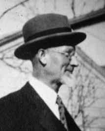 Man in suit glasses and hat poses for picture