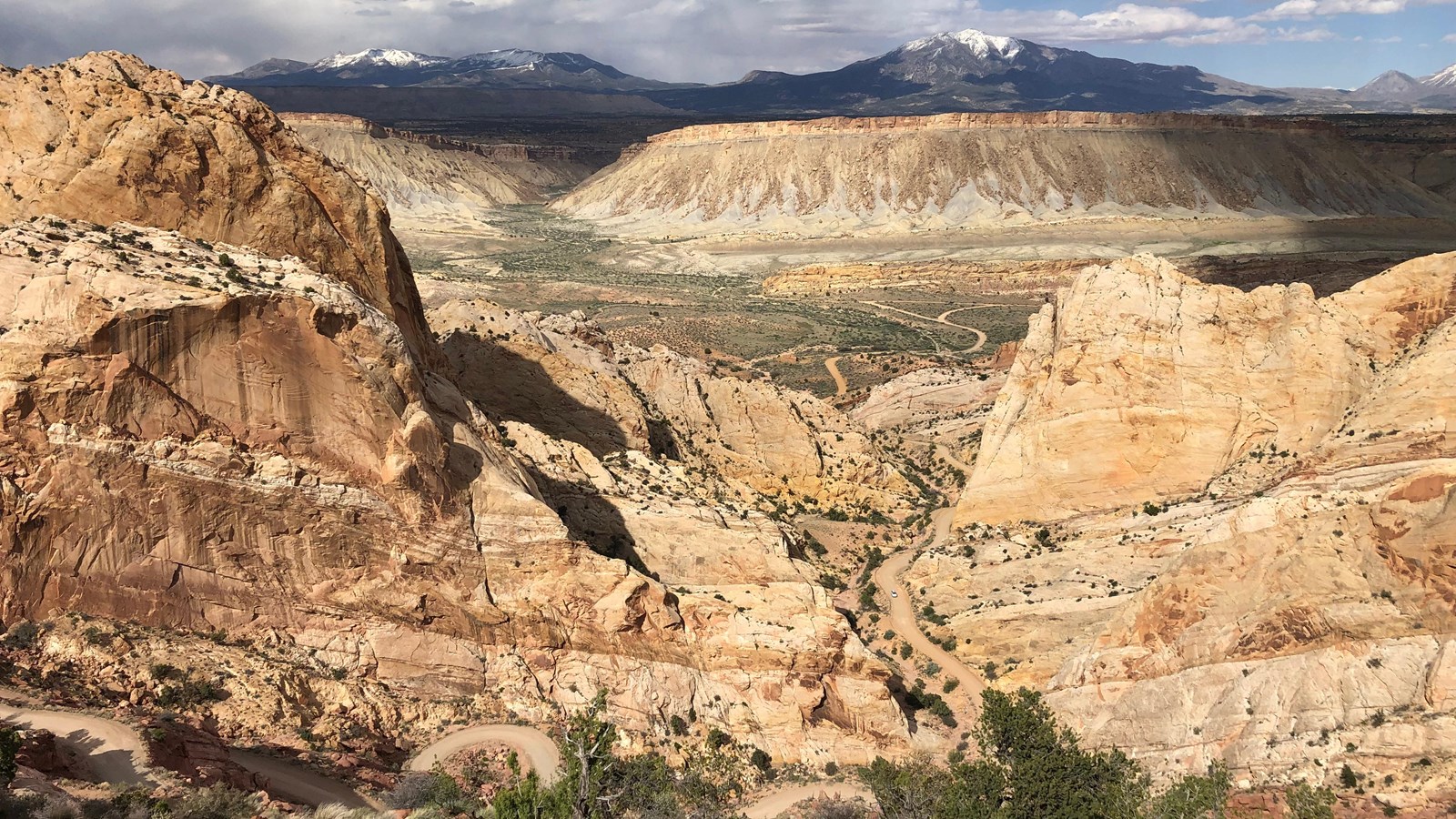 various rock layers jutting up at an angle. A valley and tall rugged mountains in the distance