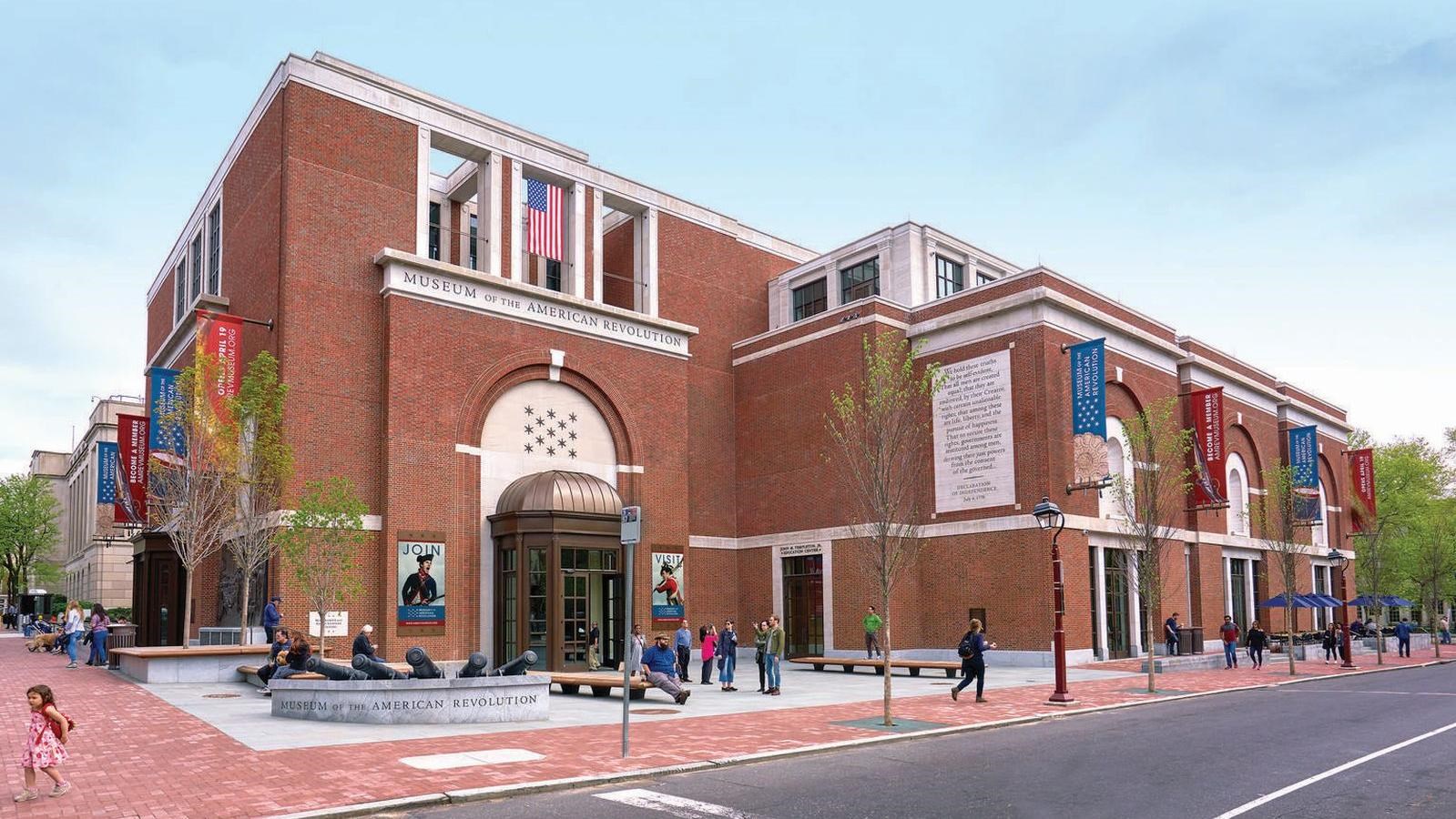 A color photo of a modern brick building with white trim and banners suspended from the wall.