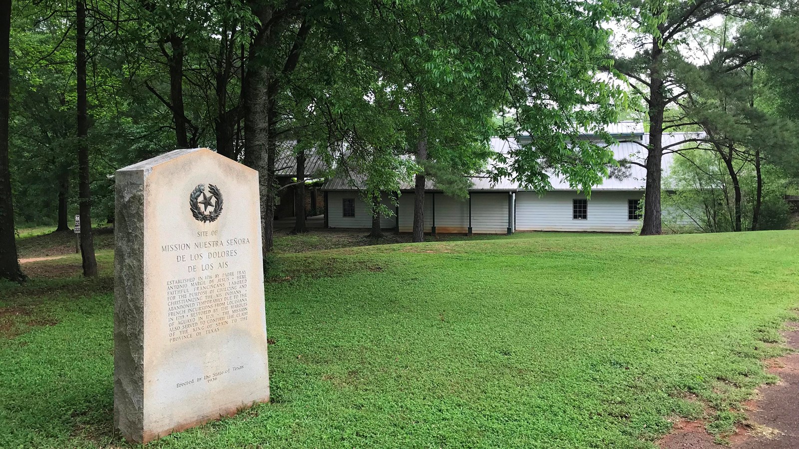 A stone marker sits in a grassy field.