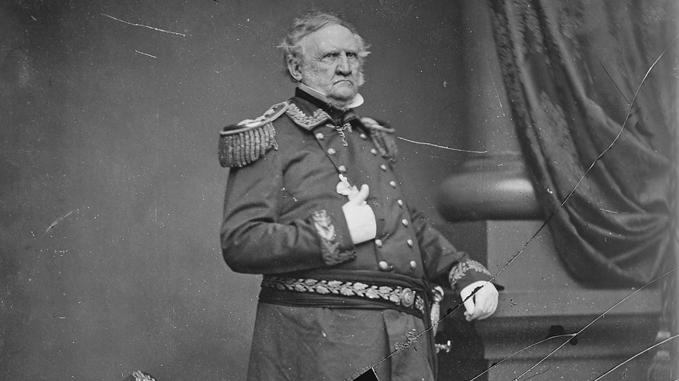 Black and white photograph of a man in military uniform with his hand to his chest.