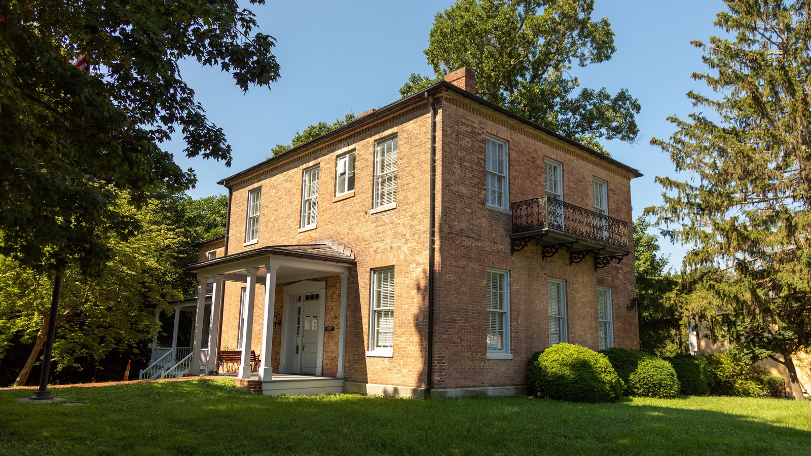 A brick house with 14 visible windows, a balcony, a front porch, and two chimneys.