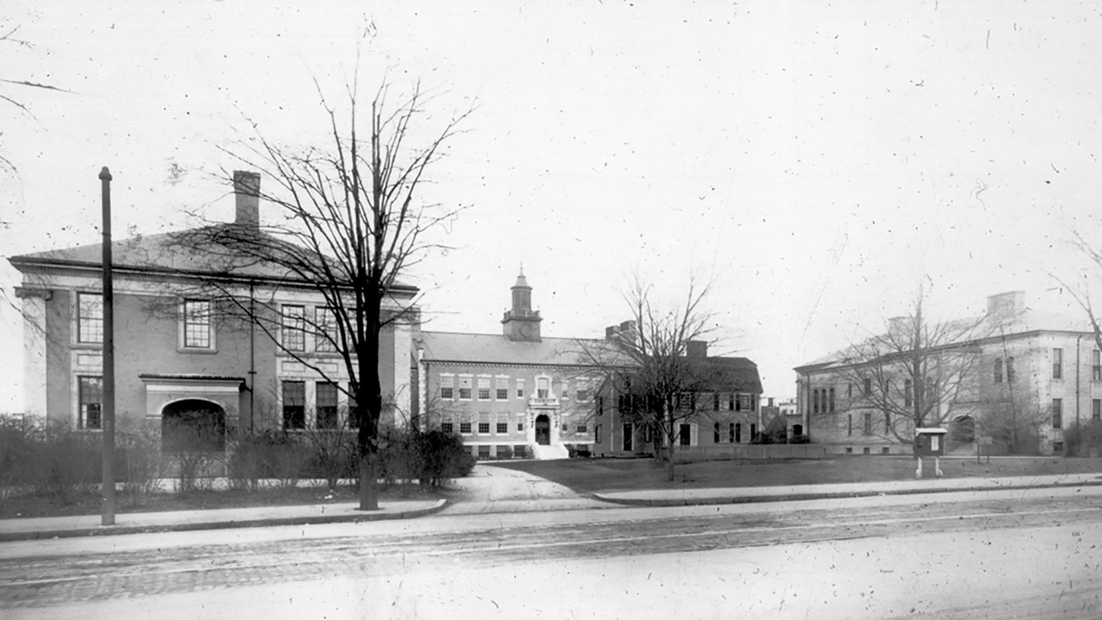 Three large school buildings arranged around historic house in courtyard