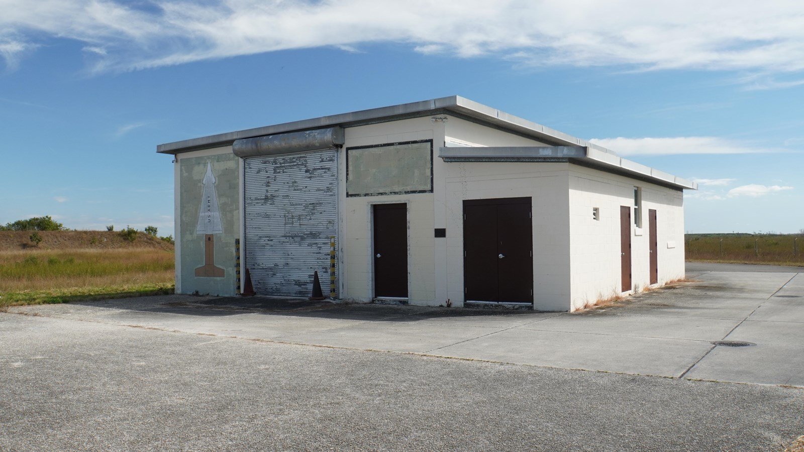 A rectangular building with brown entry doors. A large mural of a missile is painted on the side