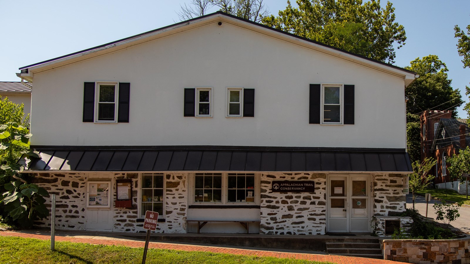A two-story white building, the first story made from stone, with six visible windows and a door.