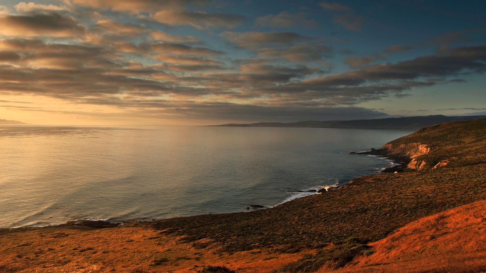 rocky coastline with low bluffs as sun rises.
