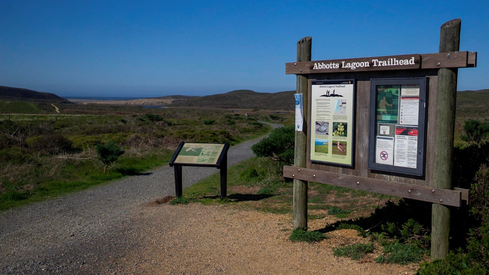 The Abbotts Lagoon trailhead bulletin board and wayside and the trail leading to lagoons and ocean.