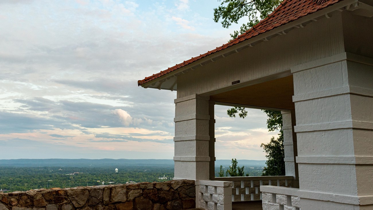A white pagoda with a red roof sits on the edge of a hillside.
