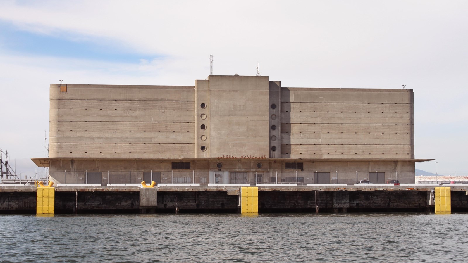 Multiple story historic building with curved sides. Dock and water.