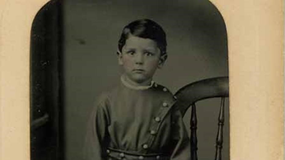 Black and white photo of a young boy in a Confederate Uniform inset in yellow paper