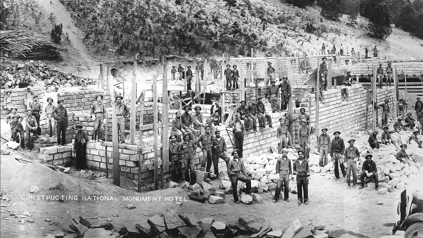 a number of people stand around a partially completed building (black and white)