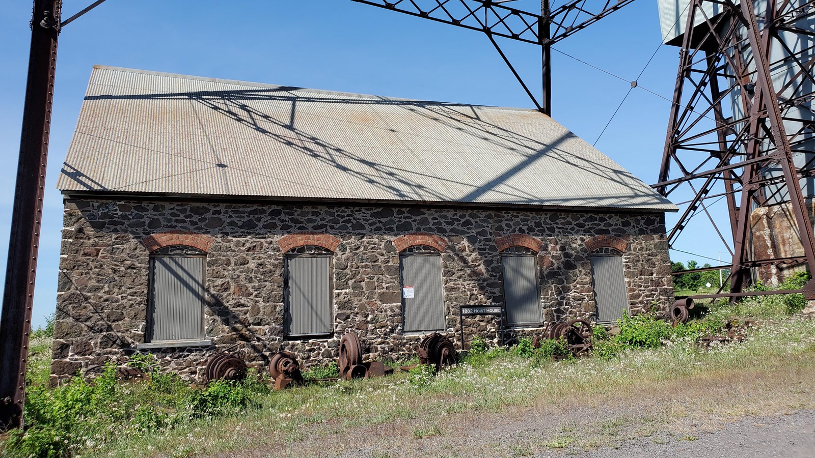 Stone building with 5 boarded windows and a metal pitched roof