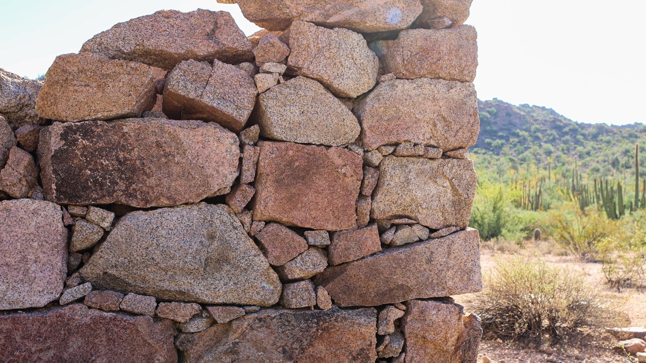 The corner of a historic, dilapidated stone building, constructed of local granite. 