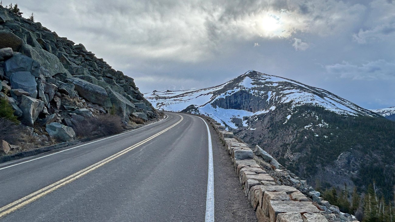 View of mountains off to the distance with a steep drop off beyond a rock-lined wall to the right