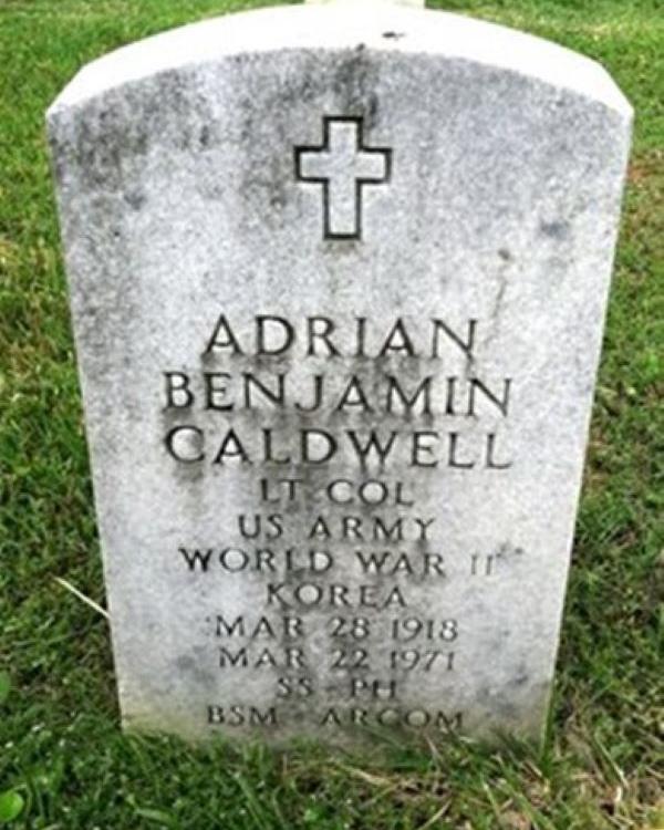 Marble headstone with cross at the top with the name "Adrian Benjamin Caldwell" on its face. 