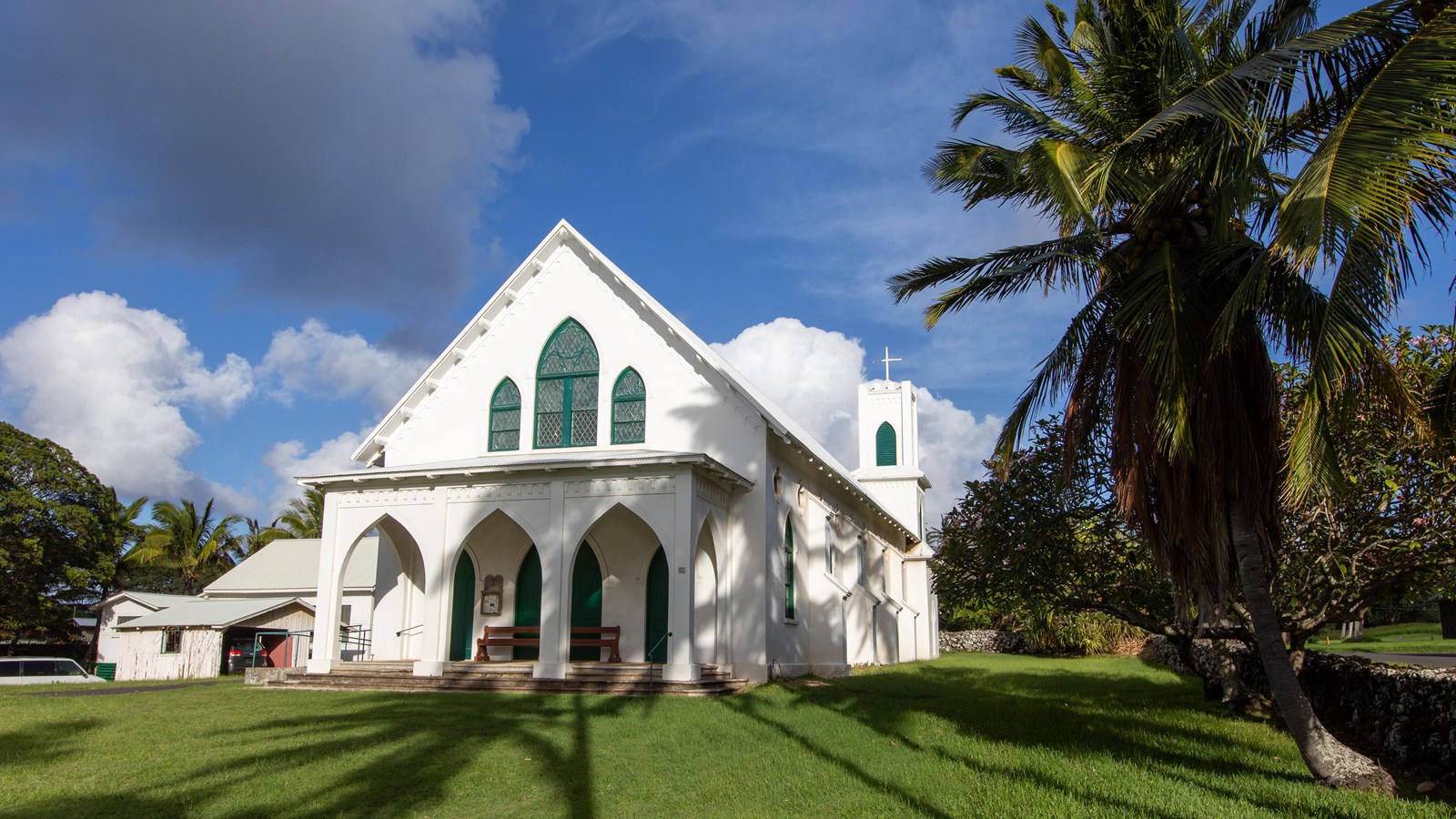 A large white building with large windows and a steeple and a large lawn out front. 