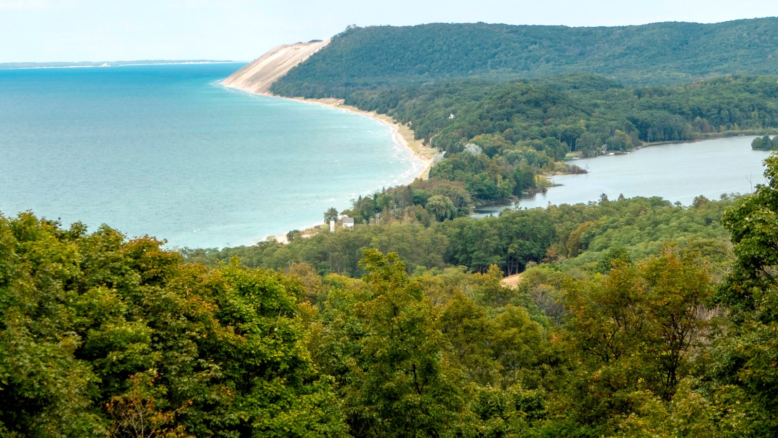 Looking over the tops of trees to a strip of green separates a large lake from a small one