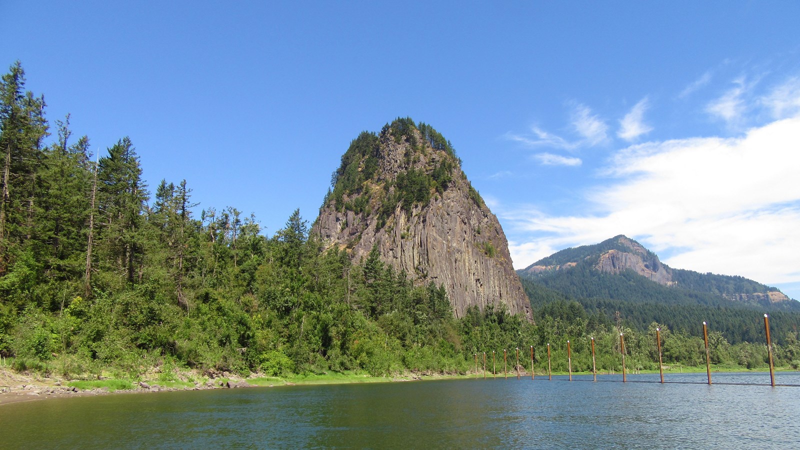 Large, tower like rock with river in the foreground. 