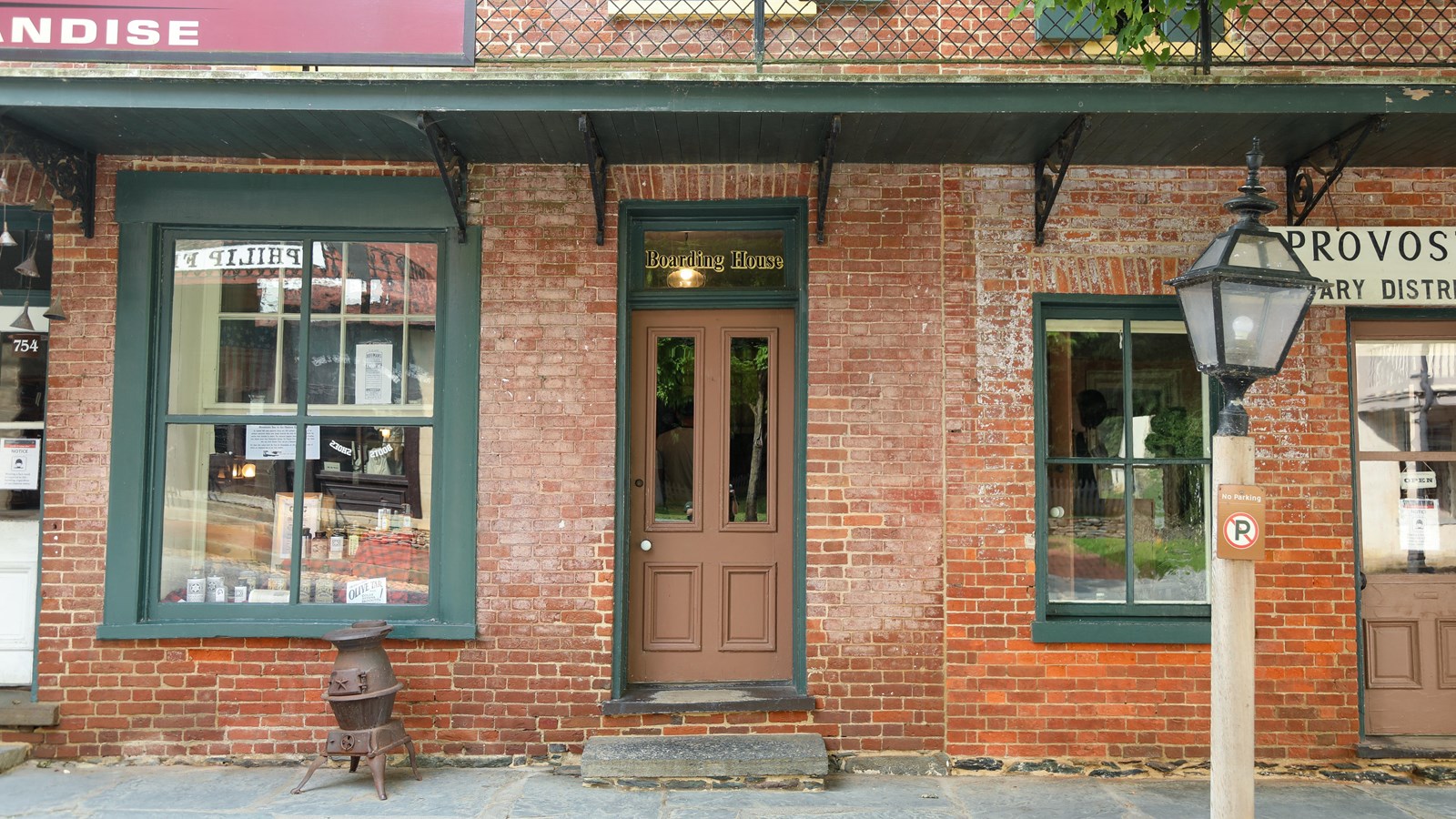 A brick storefront with two windows and two doors. Above one door are the words Boarding House.