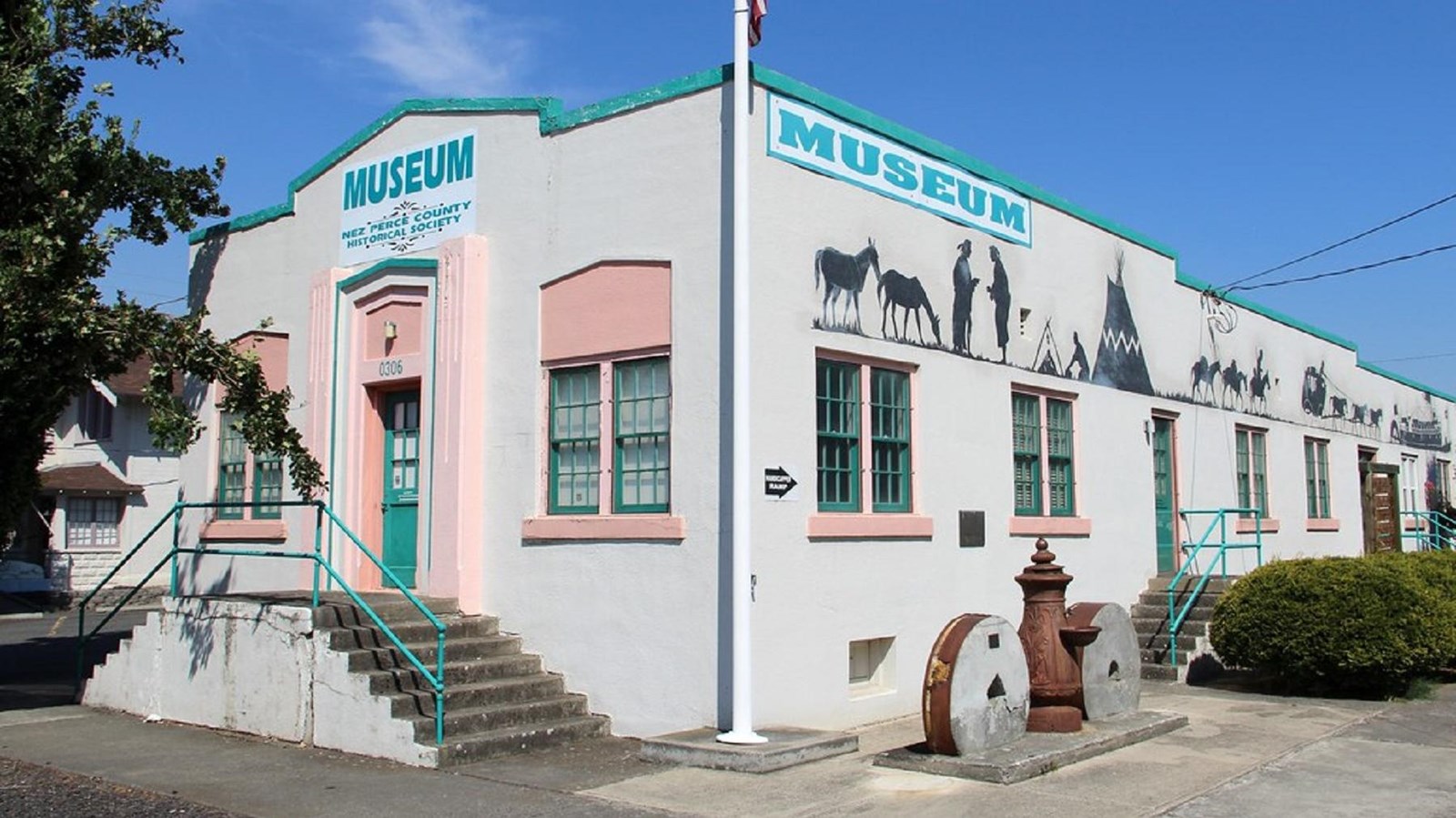 A long, rectangular, flat-roofed white building with art-deco style details around the door.