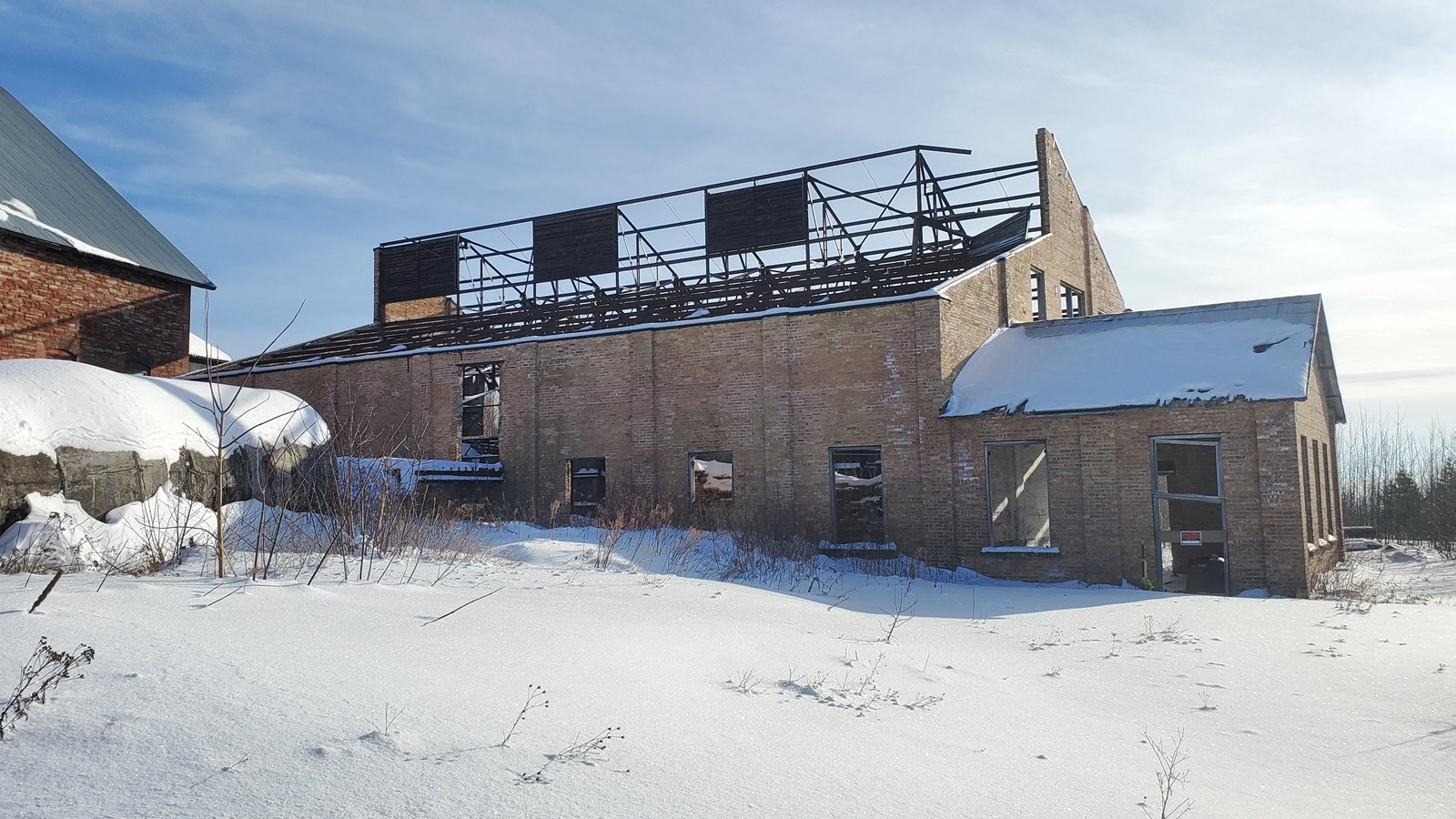 Winter scene of yellow brick building with roof partially removed.