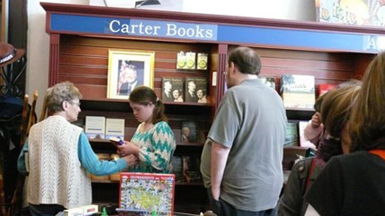 a woman assists a young girl and a man in the bookstore at Jimmy Carter NHP