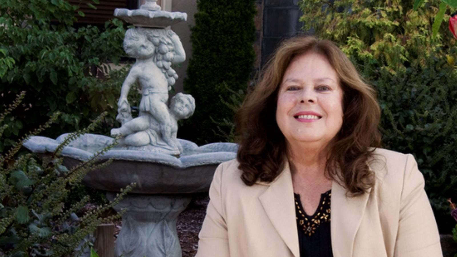 Woman sitting on chair next to fountain.