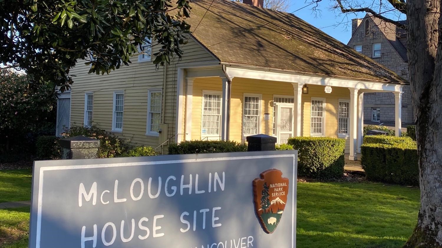 A yellow house sits in the background, behind a National Park Service sign.